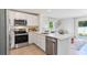 Bright kitchen featuring stainless steel appliances, white cabinets and quartz countertops, with view to the living area at 8413 Gower Trl, Wildwood, FL 34785