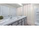 Bright bathroom featuring double sinks with a granite countertop and white cabinets at 8486 Las Palmas Way, Wildwood, FL 34785