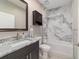 Bathroom featuring a shower with marble-like tile, granite countertop, and dark wood cabinets at 8498 Sw 129Th Terrace Rd, Dunnellon, FL 34432