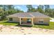 Rear exterior view shows a covered patio with sliding glass door and a home with lush landscaping at 8498 Sw 129Th Terrace Rd, Dunnellon, FL 34432