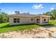 Rear exterior view features a covered patio with sliding glass door and lush landscaping at 8498 Sw 129Th Terrace Rd, Dunnellon, FL 34432
