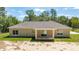 Rear exterior view of home shows a covered patio with sliding glass door and lush landscaping at 8498 Sw 129Th Terrace Rd, Dunnellon, FL 34432