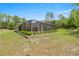 Exterior of home featuring screened in pool with shed surrounded by lush landscape at 9835 Sw 207Th Cir, Dunnellon, FL 34431