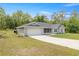 Grey home with a spacious front yard, two-car garage, and lush greenery creates a welcoming outdoor space at 9835 Sw 207Th Cir, Dunnellon, FL 34431
