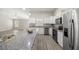 Open-concept kitchen features granite countertops, stainless steel appliances, and a view of the living area at 9835 Sw 207Th Cir, Dunnellon, FL 34431
