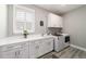 Functional laundry room with white cabinetry, counter space, a utility sink, and modern washer and dryer units at 10082 Sw 82Nd Place Rd, Ocala, FL 34481