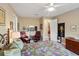 Bright bedroom with sitting area, ceiling fan, patterned bedspread and carpeted flooring at 10327 Sw 96Th Loop, Ocala, FL 34481