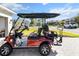 Angled view of a red golf cart, showcasing seating and side details in a suburban neighborhood at 10327 Sw 96Th Loop, Ocala, FL 34481