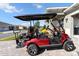 Side view of a red golf cart with a black top, parked in front of a house with stone accents at 10327 Sw 96Th Loop, Ocala, FL 34481