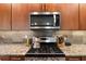 Gourmet kitchen featuring stainless steel appliances, gas range, custom tile backsplash, and granite countertops at 10327 Sw 96Th Loop, Ocala, FL 34481
