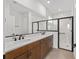 Bright bathroom features a double vanity with dark wood cabinets and a glass-enclosed shower with marble tiling at 10347 Sw 99Th Ln, Ocala, FL 34481