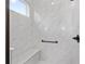 Close-up of an all-white shower featuring marble-style tile, built-in bench and a window for natural light at 10347 Sw 99Th Ln, Ocala, FL 34481