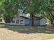 Rear view of light blue home with large tree in the backyard with partially visible water in the distance at 11025 Sw 64Th Ave, Ocala, FL 34476