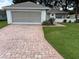Charming single-story home featuring a brick driveway, well-manicured lawn, and attached garage at 11146 Sw 68Th Ct, Ocala, FL 34476