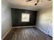 Cozy bedroom with wood floors, a window, and dark accent wall at 21135 Sw Honeysuckle St, Dunnellon, FL 34431