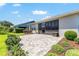 Paver patio with screened-in porch is surrounded by landscaped plantings and green grass in this lovely outdoor living space at 4379 Nw 56Th Ct, Ocala, FL 34482