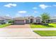 Charming single-story home with a three-car garage, paver driveway and walkway, and lush landscaping on a sunny day at 4379 Nw 56Th Ct, Ocala, FL 34482