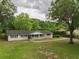 View of a single-story home with black shutters, a covered porch, and a large grassy yard at 4430 Se 47Th Pl, Ocala, FL 34480