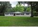 A ranch-style house featuring a welcoming front porch, dark shutters, and a lush green lawn at 4430 Se 47Th Pl, Ocala, FL 34480