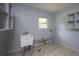 Laundry room with a utility sink, window and tiled floors, with storage shelves at 4430 Se 47Th Pl, Ocala, FL 34480