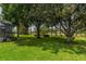Lush backyard with mature trees and partial view of the screened pool at 4530 Nw 78Th Ave, Ocala, FL 34482