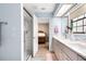 Bright bathroom featuring a double vanity, glass-enclosed shower, and a glimpse into the Primary bedroom at 4530 Nw 78Th Ave, Ocala, FL 34482