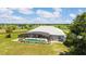 Aerial view showcases screened-in pool with lush lawn, and neighboring farm land in the distance at 5489 Nantahala Ln, Lady Lake, FL 32159
