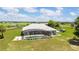 Aerial view of screened-in pool, bordered with green shrubbery, with a lush green field extending to neighboring properties at 5489 Nantahala Ln, Lady Lake, FL 32159