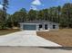 A welcoming house featuring a front-facing two car garage, covered entrance and long driveway at 6178 Sw 207Th Ct, Dunnellon, FL 34431