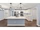 Open kitchen with large island, stainless appliances, white cabinets, and modern pendant lighting at 6570 Sw 129Th Loop, Ocala, FL 34473