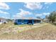 Rear view of a blue single-story home featuring a screened-in patio and spacious yard at 6570 Sw 129Th Loop, Ocala, FL 34473