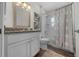 Updated bathroom with granite vanity, decorative floral accents, and shower with grey patterned curtain at 6791 Se 100Th Pl, Belleview, FL 34420