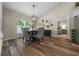 A dining room has four patterned chairs, a dark table, a modern chandelier, and lots of natural light at 6791 Se 100Th Pl, Belleview, FL 34420