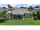 Rear exterior of this home features an enclosed lanai, lush landscaping, and a spacious, well-maintained lawn at 8545 Se 168Th Kittredge Loop, The Villages, FL 32162