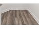 Close-up of stylish gray wood flooring featuring detailed wood grain and white baseboards at 9871 Sw 105Th Ct, Ocala, FL 34481