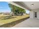 A spacious green backyard with mature trees, showing the home's back exterior and covered patio at 10081 Se 68Th Ct, Belleview, FL 34420