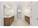 Bathroom featuring double sinks with wood cabinets, white countertops and large mirrors with lights at 10556 Sw 96Th Lane Rd, Ocala, FL 34481