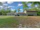 Large backyard with a gray home, patio furniture under an umbrella, and an expansive lawn with surrounding trees at 11806 Sw 61St Place Rd, Ocala, FL 34481