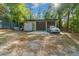 Two-car garage with tan siding, a silver car parked on the concrete pad, and storage containers nearby at 11806 Sw 61St Place Rd, Ocala, FL 34481