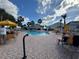 Outdoor pool area with lounge chairs and umbrellas near the clubhouse, surrounded by palm trees under a sunny sky at 11945 Se 171St Loop, Summerfield, FL 34491