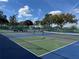 Well-maintained tennis courts with blue and green surfaces, nets, benches and surrounding trees under a blue sky at 11945 Se 171St Loop, Summerfield, FL 34491