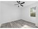 A simple, bright bedroom with light gray flooring, a ceiling fan, and a view of the outdoors at 12689 Sw 81St St, Dunnellon, FL 34432