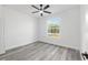 Cozy bedroom with wood-look flooring, neutral paint, a ceiling fan and a window overlooking the trees at 12689 Sw 81St St, Dunnellon, FL 34432
