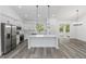 A spacious, open-concept kitchen featuring white cabinets, stainless appliances, and a center island with modern pendant lighting at 12689 Sw 81St St, Dunnellon, FL 34432