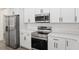 Modern kitchen features stainless appliances, white cabinetry, quartz countertops, and sleek black hardware at 12689 Sw 81St St, Dunnellon, FL 34432