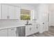 Close-up of a kitchen area featuring white cabinets, stainless steel appliances, and a large window with a wooded view at 12689 Sw 81St St, Dunnellon, FL 34432