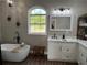 Modern bathroom with a soaking tub, white vanity with marble countertop, and a large window providing ample natural light at 13430 Ne 30Th Ct, Anthony, FL 32617