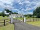 Attractive home with a metal gate at the driveway entrance, a side-entry garage, and a lush green lawn at 13430 Ne 30Th Ct, Anthony, FL 32617