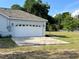 A white garage door on a gray home features a driveway and yard at 13430 Ne 30Th Ct, Anthony, FL 32617