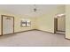 Open living room featuring neutral carpet, a ceiling fan, a window, and access to the front door at 14555 Se 98Th Ave, Summerfield, FL 34491